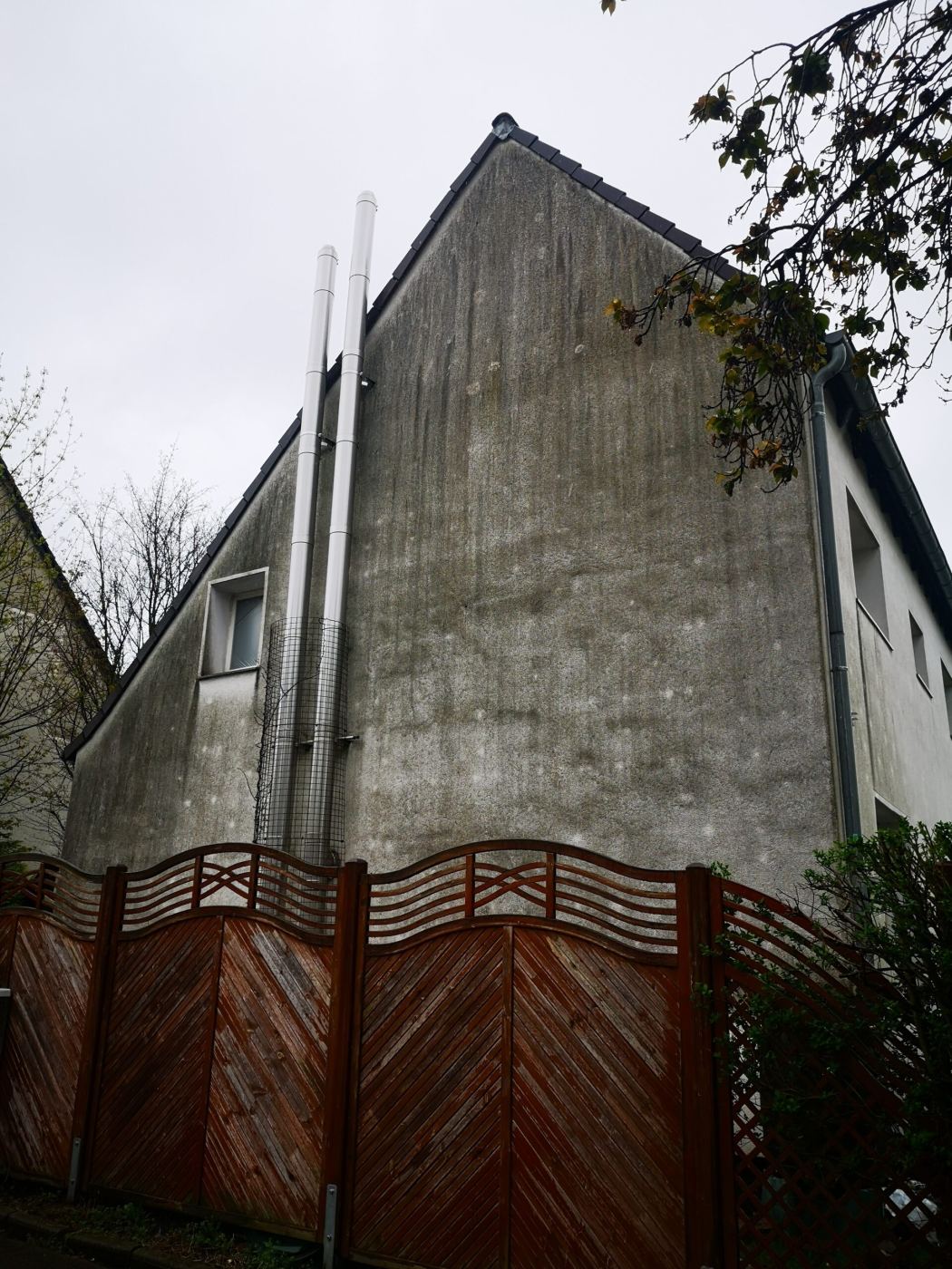 Vorher: Giebelwand grau und bewachsen